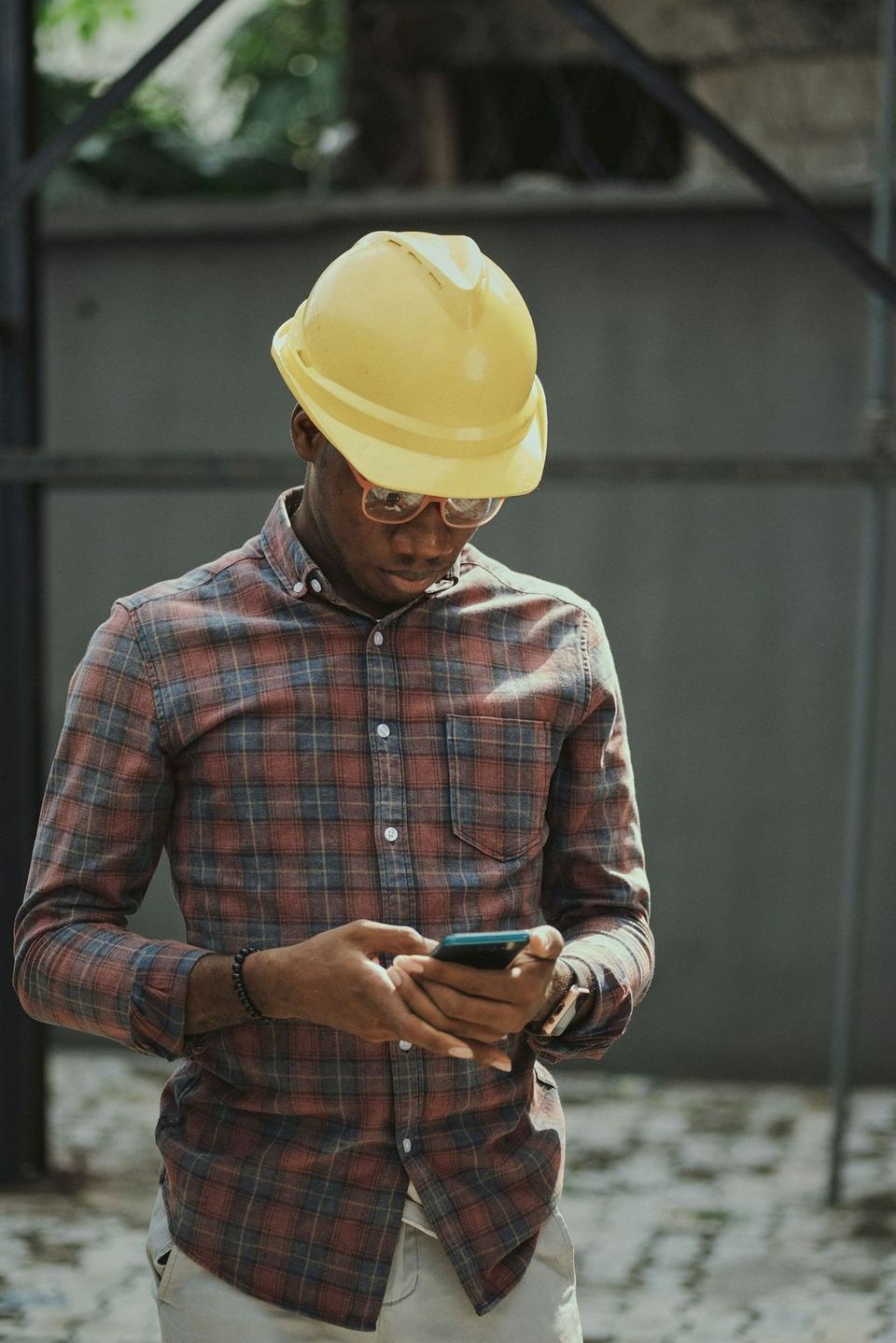 A contractor in a hard hat checking his phone on site
