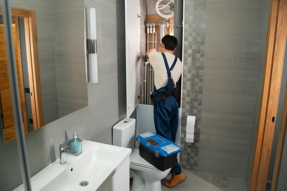A plumber repairing pipes in a bathroom